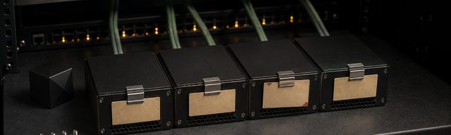 Dark 19-inch rack with FrankenPHP worker hosts: matte-black edge boxes, sage-green patch cables landing on the switch ports, a module cartridge with a kraft-paper mono label and a single oxblood tag. The switch front panel's status LEDs glow in a calm pulsing rhythm, the right half of the frame fades to near-black and leaves negative space for the title overlay.